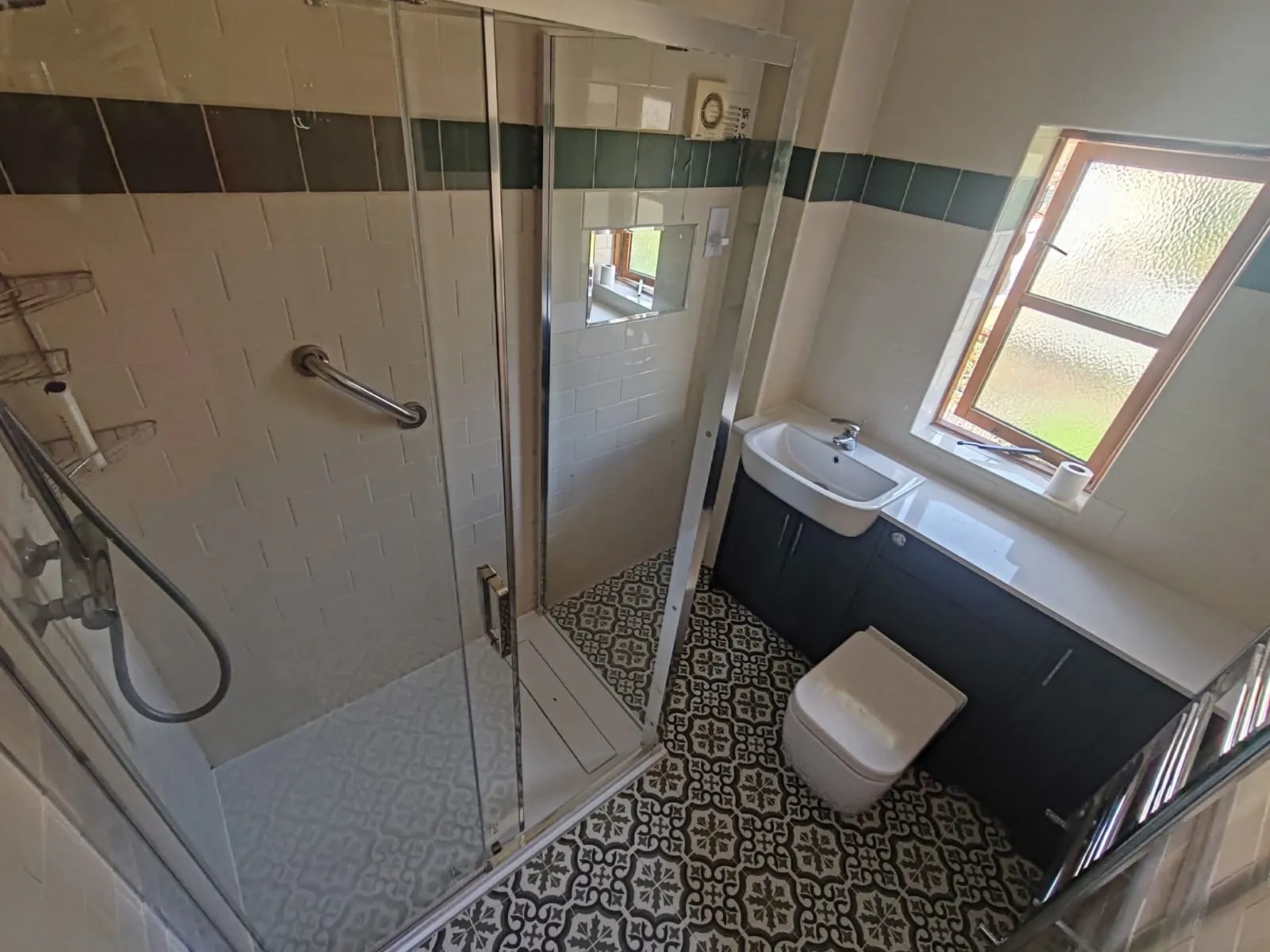 A well-lit bathroom containing a sink, toilet, and shower, emphasizing a simple and organized design