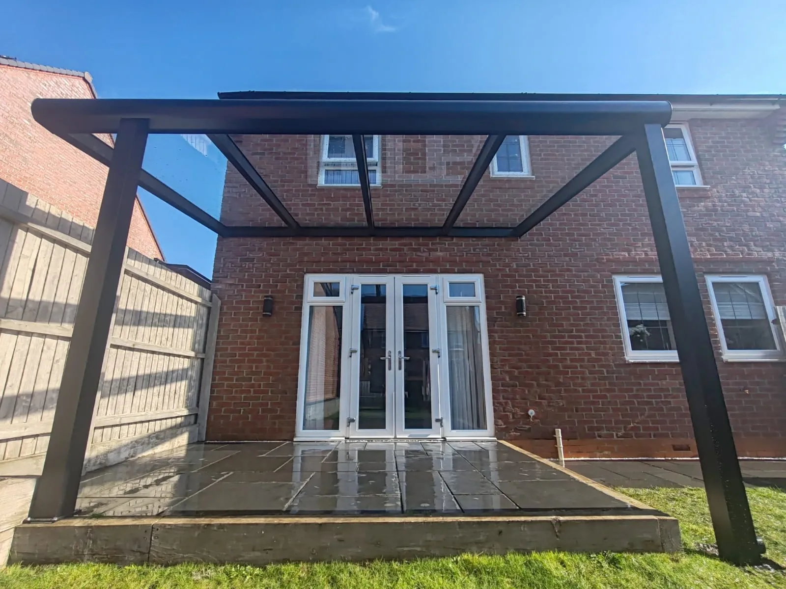 A sleek patio with a black canopy above, showcasing a contemporary glass-roofed terrace design.