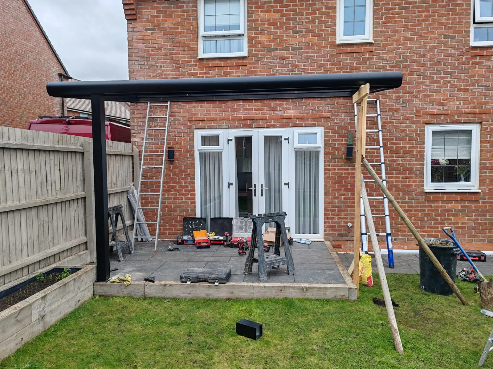 An under-construction patio featuring a roof and a ladder, highlighting the development of a beautiful outdoor terrace.