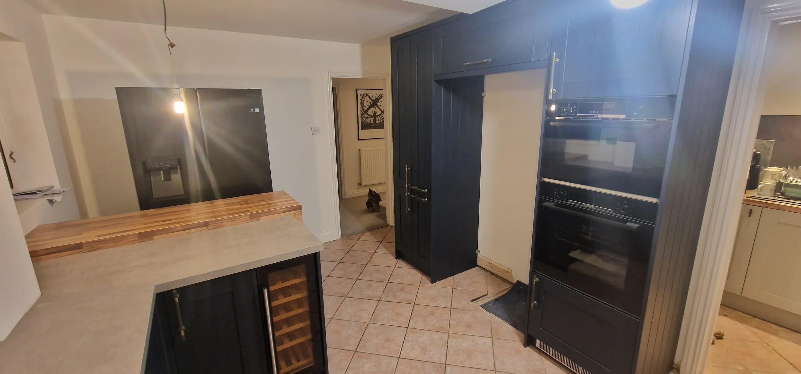 Contemporary kitchen showcasing a sink, refrigerator, double ovens, and newly installed floor-to-ceiling cupboards