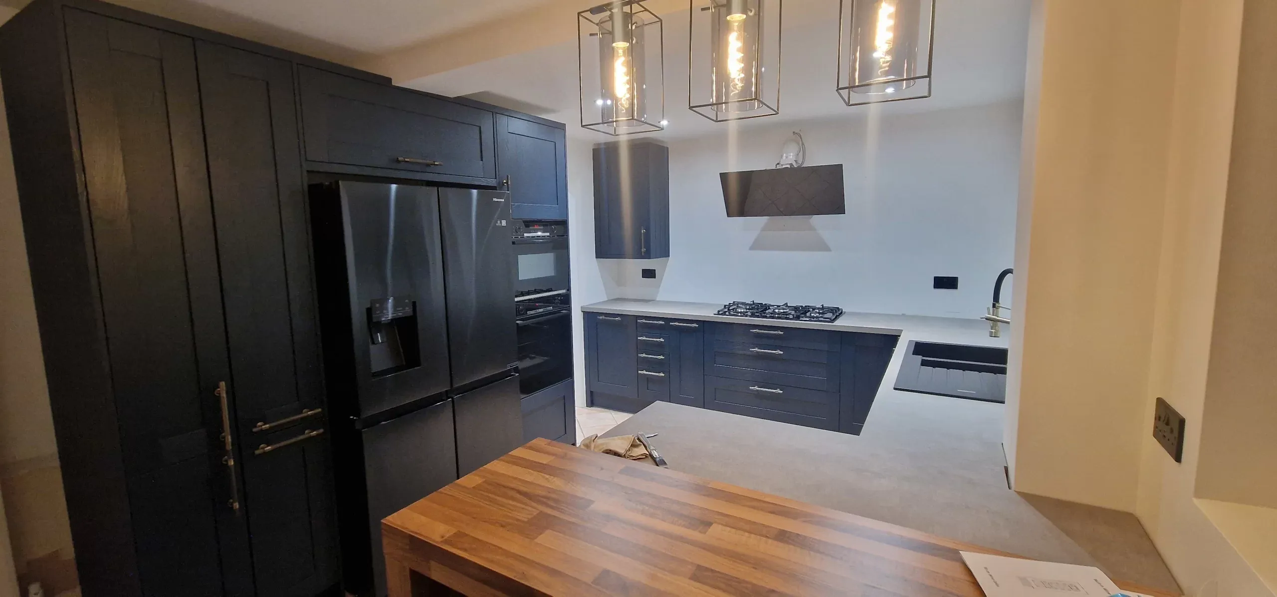 Modern kitchen featuring sleek black cabinets and a new refrigerator, showcasing a completed remodelling project.