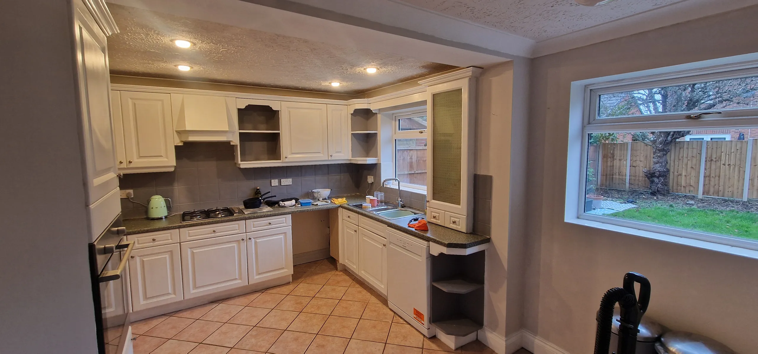 An outdated kitchen showcasing a sink, stove, and cabinets, poorly utilizing available space and storage options.
