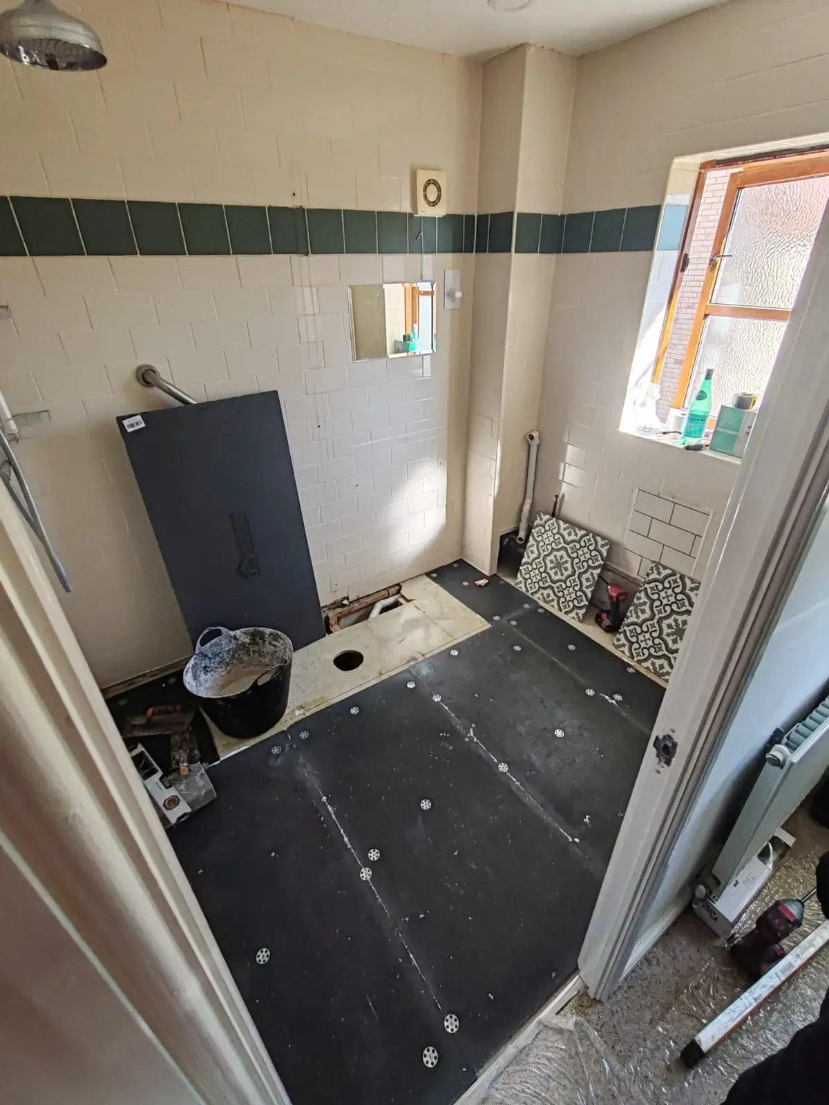 Renovation in progress in a bathroom, showcasing a shower and toilet amidst tools and materials.